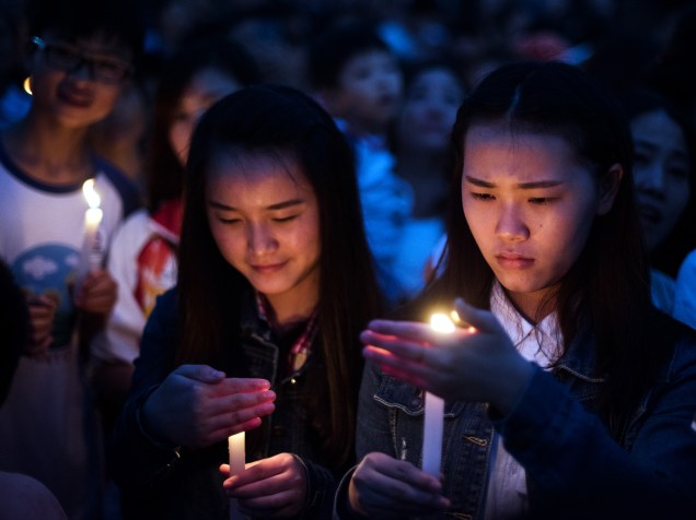 Pessoas acendem velas durante vigília em homenagem às vítimas do naufrágio no rio Yang Tsé