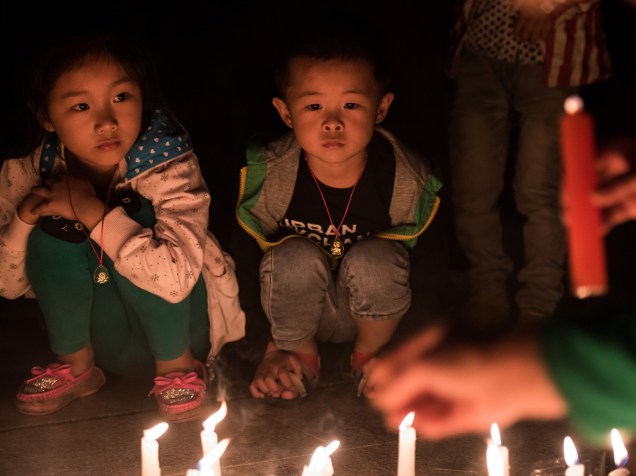 Crianças participam de vigília em homenagem às vítimas do naufrágio em Yang Tsé