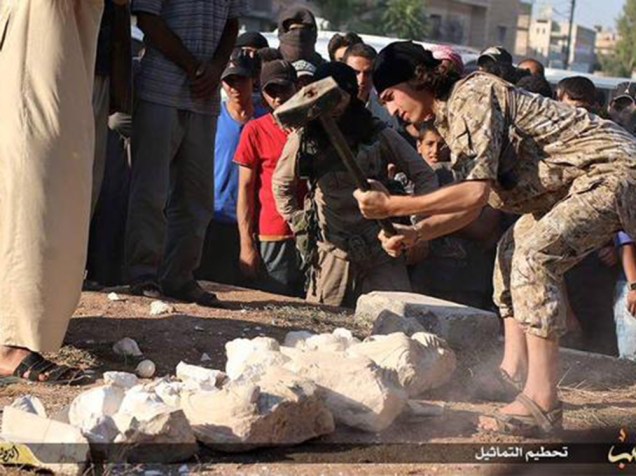 <p>Em Aleppo, um militante do Estado Islâmico destrói estátuas que seriam contrabandeadas da cidade histórica de Palmira, na Síria</p>