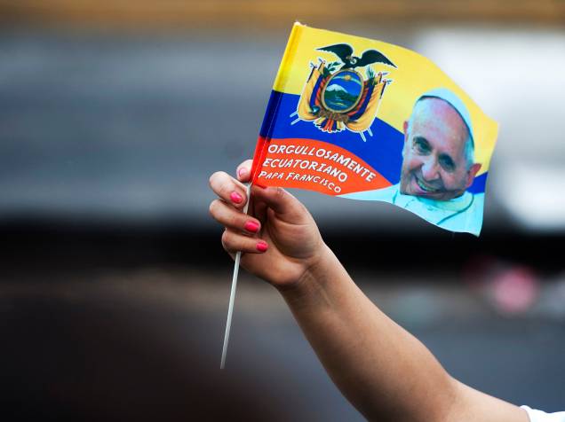 Fiel segura uma bandeira do Equador com a foto do Papa Francisco enquanto o líder da Igreja Católica desfila com papamóvel pelas ruas de Quito - 05/07/2015