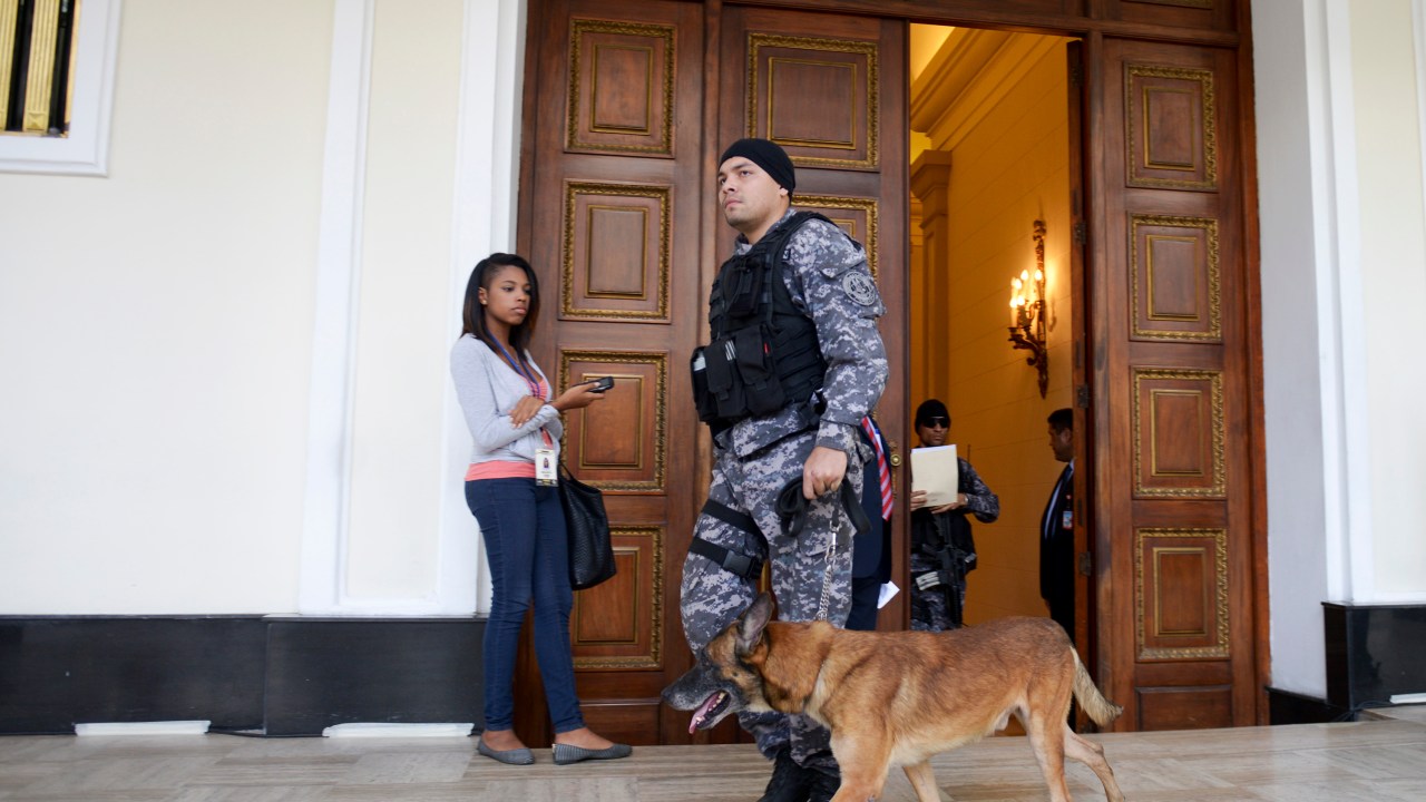 Um membro do Serviço de Inteligência Bolivariana anda com um cão por um corredor da Assembleia Nacional em Caracas. Três bombas panfletárias explodiram nos arredores do local sem deixar vítimas - 26/01/2016