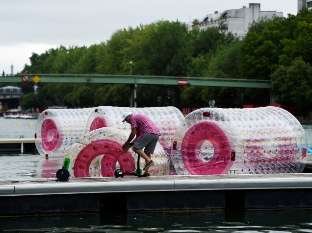 Homem prepara bolhas de plástico para realização de atividades nas docas Villette, às margens do Rio Sena em Paris, durante a inauguração da 14ª edição do Paris Plages