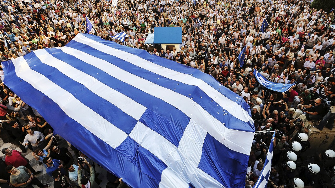 Manifestantes carregam uma bandeira grega durante um comício em Atenas pedindo ao governo para fechar um acordo com seus credores internacionais
