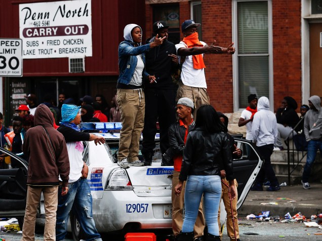 Manifestantes sobem em uma viatura policial destruída durante protestos em Baltimore (EUA) - 27/04/2015