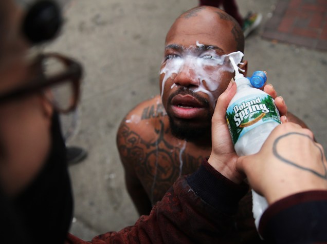 Homem limpa os olhos de um manifestante atingido por spray de pimenta da polícia durante protestos que seguiram ao funeral do jovem negro Freddie Gray em Baltimore (EUA) - 27/04/2015