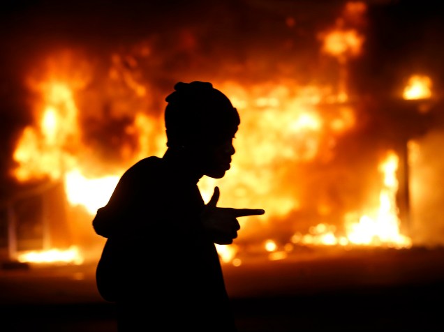 Homem passa por um edifício incendiado em meio a protestos em Ferguson, Missouri, após decisão do júri de não indiciar um policial pela morte de Michael Brown, um jovem negro desarmado - 24/11/2014