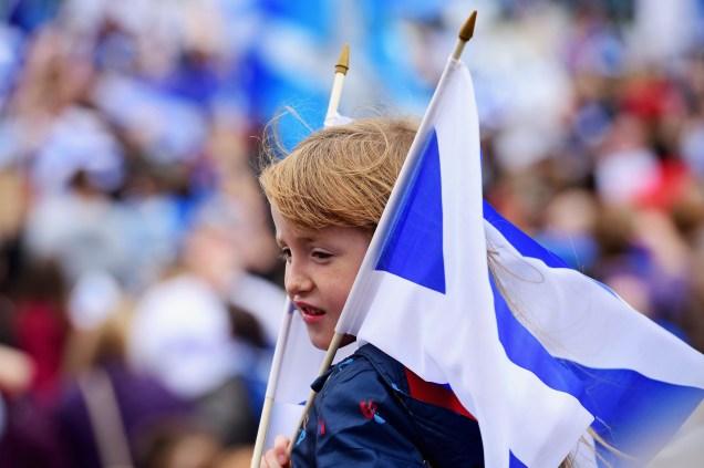 Garoto segura bandeiras pró-independência em marcha até a BBC Scotland em Glasgow, Escócia - 14/09/2014