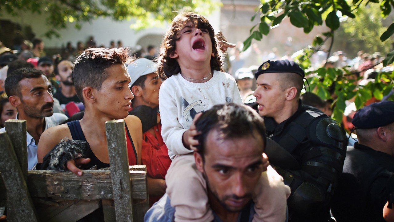 Criança chora nos ombros de seu pai enquanto eles tentam atravessar um bloqueio policial para chegar à estação de Tovarnik na tentativa de embarcar em um trem com destino a Zagreb, na Croácia - 17/09/2015