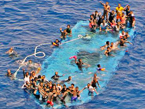 Migrantes são vistos em um barco parcialmente submerso, antes de serem resgatados pelo, Reina Sofia ao largo da costa da Líbia