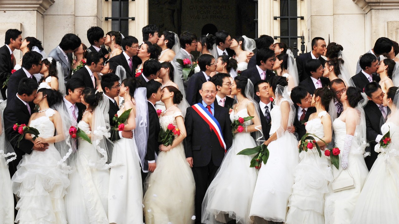 O então prefeito da cidade francesa de Tours, Jean Germain, aparece em uma foto feita em 2009 com um grupo de 31 casais chineses em frente à Câmara Municipal do município