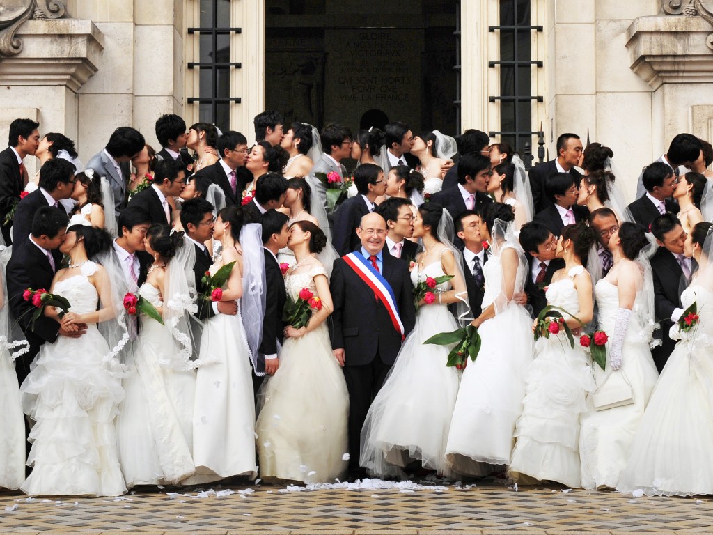 O então prefeito da cidade francesa de Tours, Jean Germain, aparece em uma foto feita em 2009 com um grupo de 31 casais chineses em frente à Câmara Municipal do município