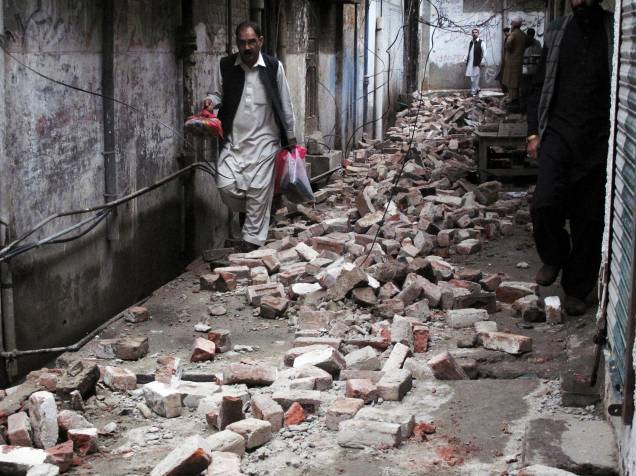 Homem caminha entre os escombros de uma casa danificada por um terremoto em Mingora, Swat, no Paquistão - 26/10/2015