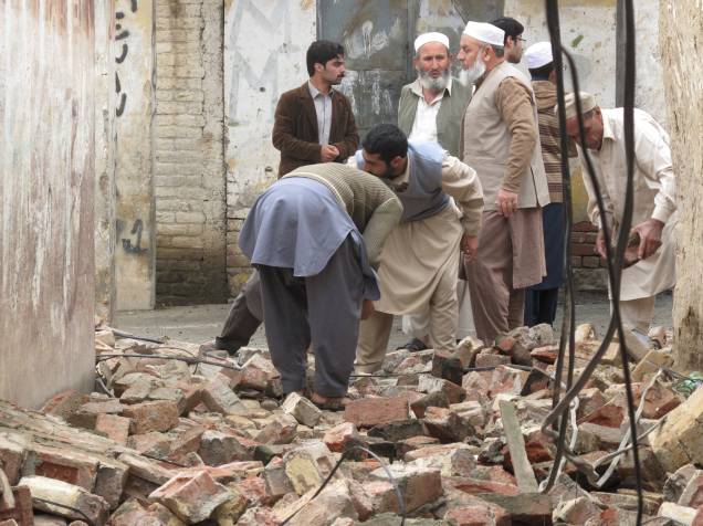 Moradores se reúnem para abrir um caminho através da remoção de escombros de uma casa depois que ela foi danificada por um terremoto em Mingora, Swat, Paquistão