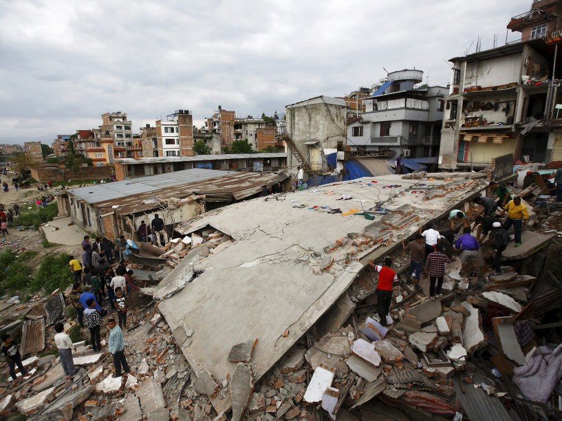 Pessoas se reúnem perto de uma casa que desabou após o terremoto de magnitude 7,8 em Katmandu, Nepal - 25/04/2015