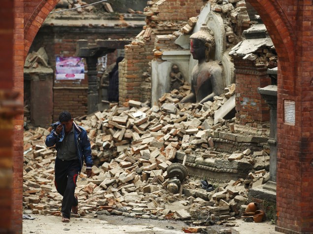 Homem chora enquanto caminha próximo a uma estátua de Buda em um santuário danificado pelo terremoto em Bhaktapur, Nepal - 26/04/2015