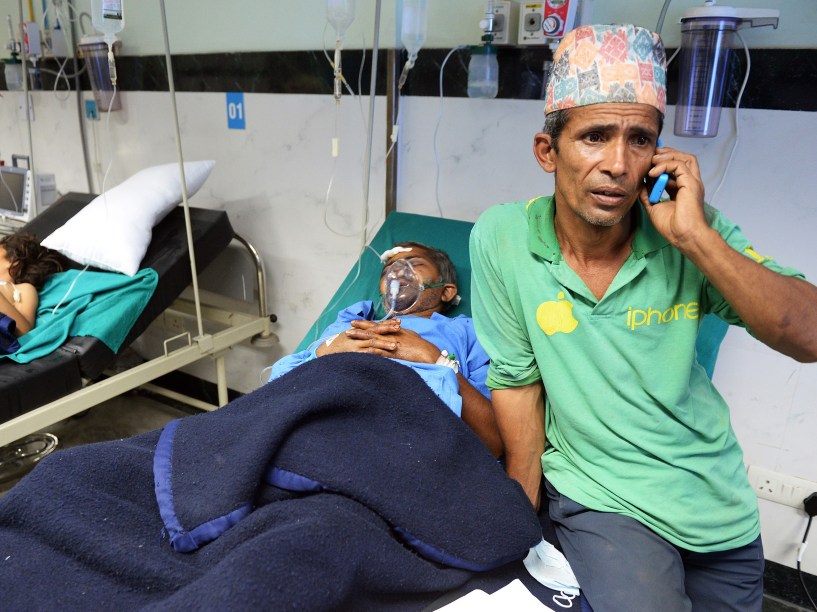 Homem fala ao telefone enquanto seu familiar recebe atendimento em um hospital de Katmandu - 26/04/2015