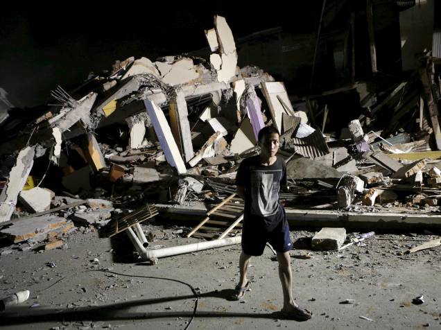Menino caminha próximo a um hotel que desabou após o terremoto que atingiu a costa do Pacífico, em Portoviejo, no Equador - 17/04/2016