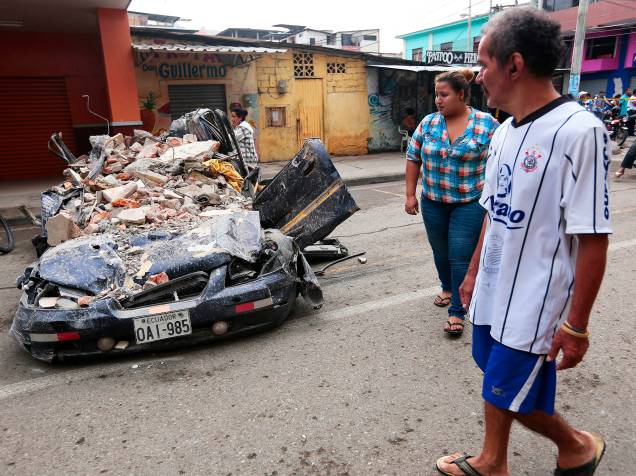 Moradores da cidade de Portoviejo, no Equador, caminham próximo a um carro, destruído após forte terremoto atingir o país. Ao menos 230 pessoas morreram - 17/04/2016