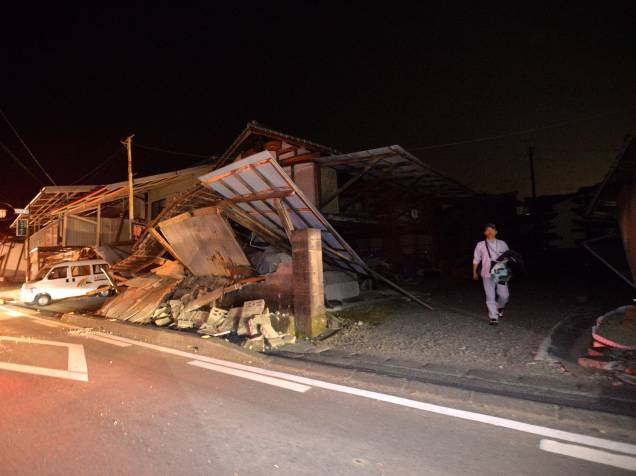 Homem caminha próximo a uma casa destruída após forte tremor que atingiu a cidade de Kumamoto, sudoeste do Japão - 14/04/2016
