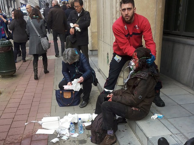 Homem ajuda uma mulher ferida do lado de fora da estação de metrô Maelbeek em Bruxelas, após ataque terrorista no local - 22/03/2016