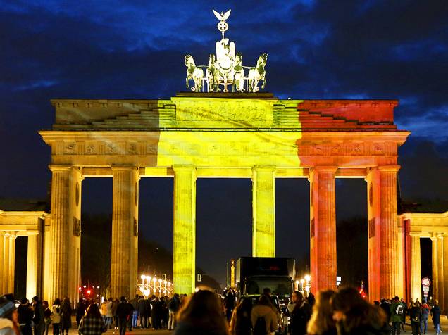 Belgas em frente ao Portão de Brandemburgo, iluminado com as cores da bandeira do país (vermelho, amarelo e preto), em tribuno às vítimas dos atentados em Bruxelas, nesta terça-feira (22). O grupo Estado Islâmico assumiu a autoria dos ataques