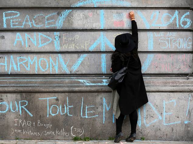 Mulher escreve mensagens de apoio, em parede da Bolsa de Valores de Bruxelas, aos familiares que perderam seus parentes nos atentados, nesta quarta-feira (23)