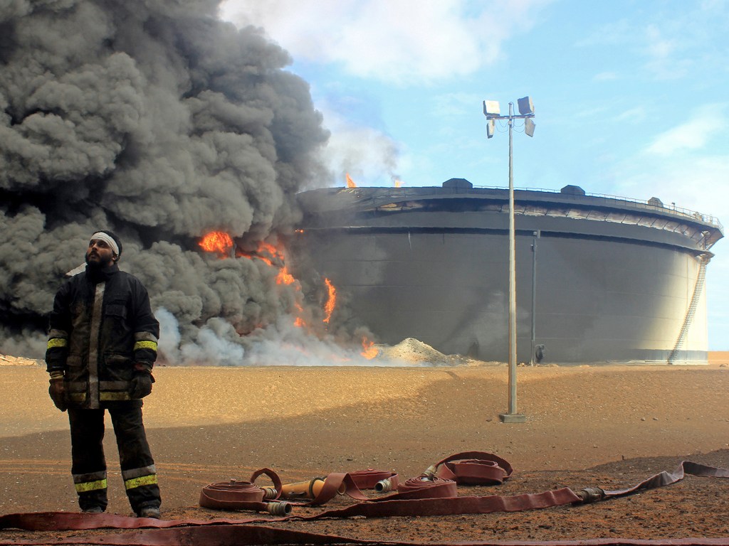 Bombeiros trabalham para extinguir um incêndio provocado por jihadistas do Estado Islâmico em uma instalação petrolífera na cidade de Ras Lanuf, norte da Líbia - 23/01/2016