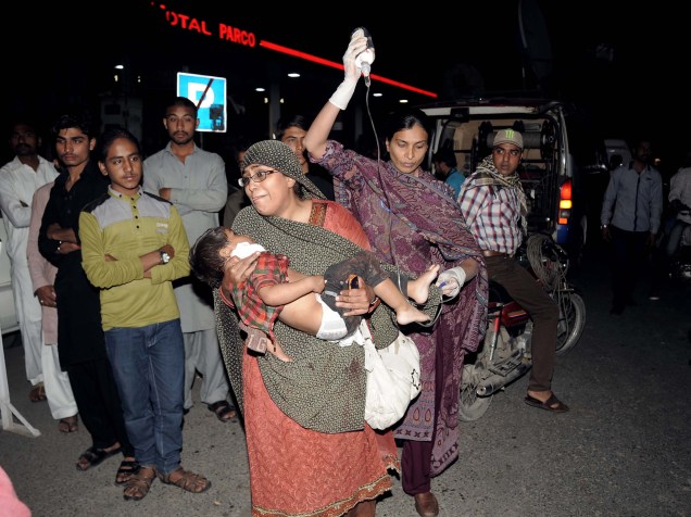 Mulher carrega uma criança ferida para o hospital, após atentado a bomba em Lahore, no Paquistão - 27/03/2016
