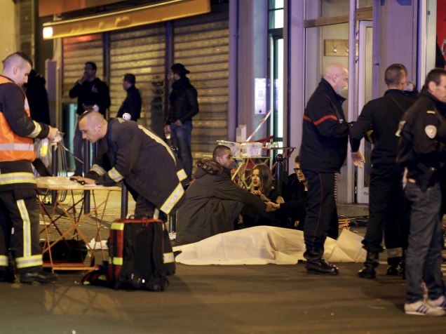 Serviços de resgate trabalham perto dos corpos cobertos fora de um restaurante na sequência de um tiroteio em Paris, França - 13/11/2015