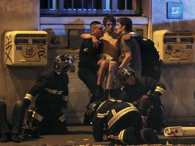 Bombeiros ajudam um homem ferido nos arredores da sala de concertos Bataclan na sequência de um tiroteio em Paris, França - 13/11/2015