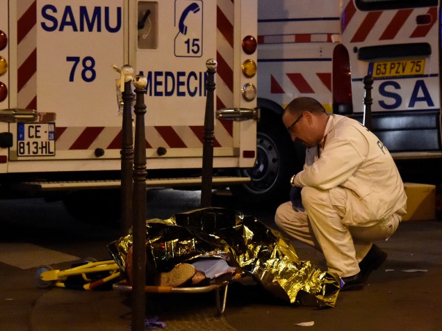 Socorrista fala com uma pessoa ferida em uma maca, perto da sala de concertos Bataclan no centro de Paris - 13/11/2015