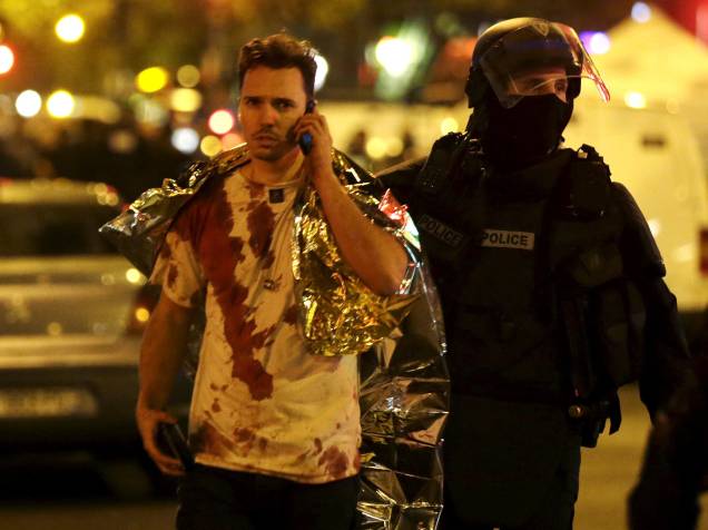Policial auxilia uma vítima coberta de sangue perto da sala de concertos Bataclan após os ataques em Paris - 13/11/2015