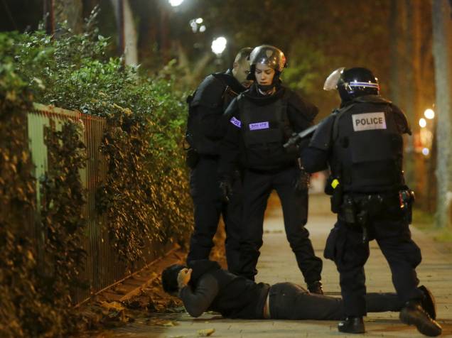 Homem fica no chão enquanto a policiais verificam sua identidade nos arredores da sala de concertos Bataclan na sequência de tiroteios  em Paris, França - 13/11/2015