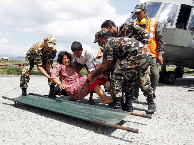 Soldados do exército levam mulher ferida durante terremoto para uma base comunitária no aeroporto de Katmandu - 27/04/2015