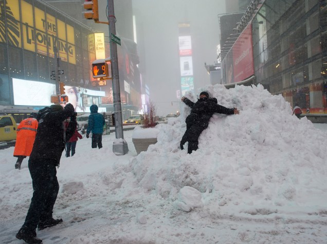 Criança brinca na neve em Nova York e cobre a cidade de branco, neste sábado (23)
