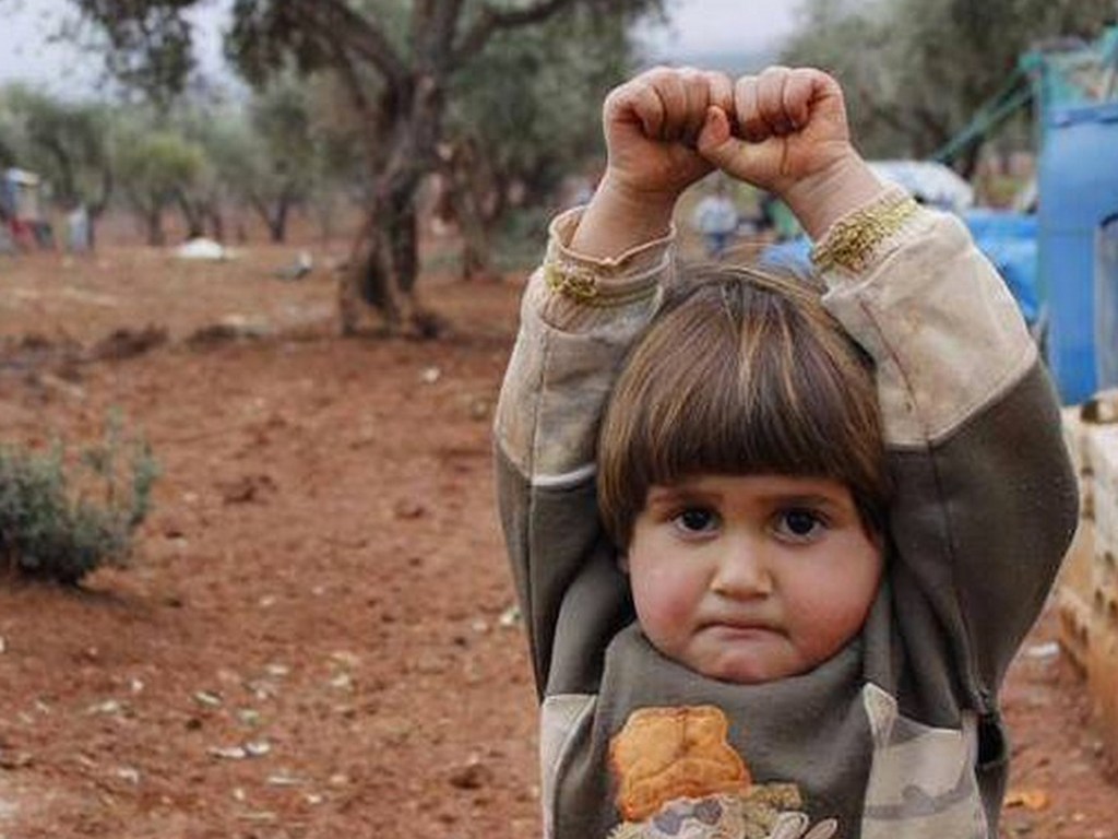 A foto de uma criança com as mãos para cima no campo de refugiados de Atmeh, na Síria