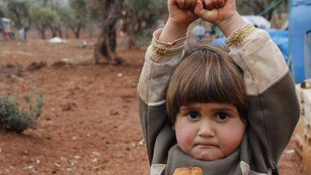 A foto de uma criança com as mãos para cima no campo de refugiados de Atmeh, na Síria