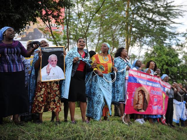 Mulheres católicas cantam ao lado de uma estrada enquanto seguram faixas de boas-vindas ao papa Francisco, em Nairóbi, Quênia