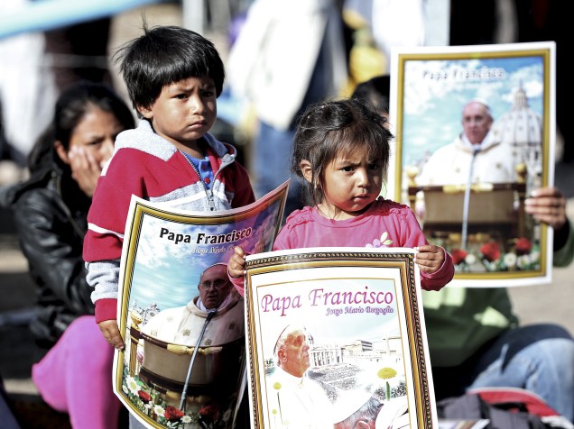 Crianças carregam cartazes com imagem do papa Francisco durante sua chegada ao Santuário El Quinche, no Equador