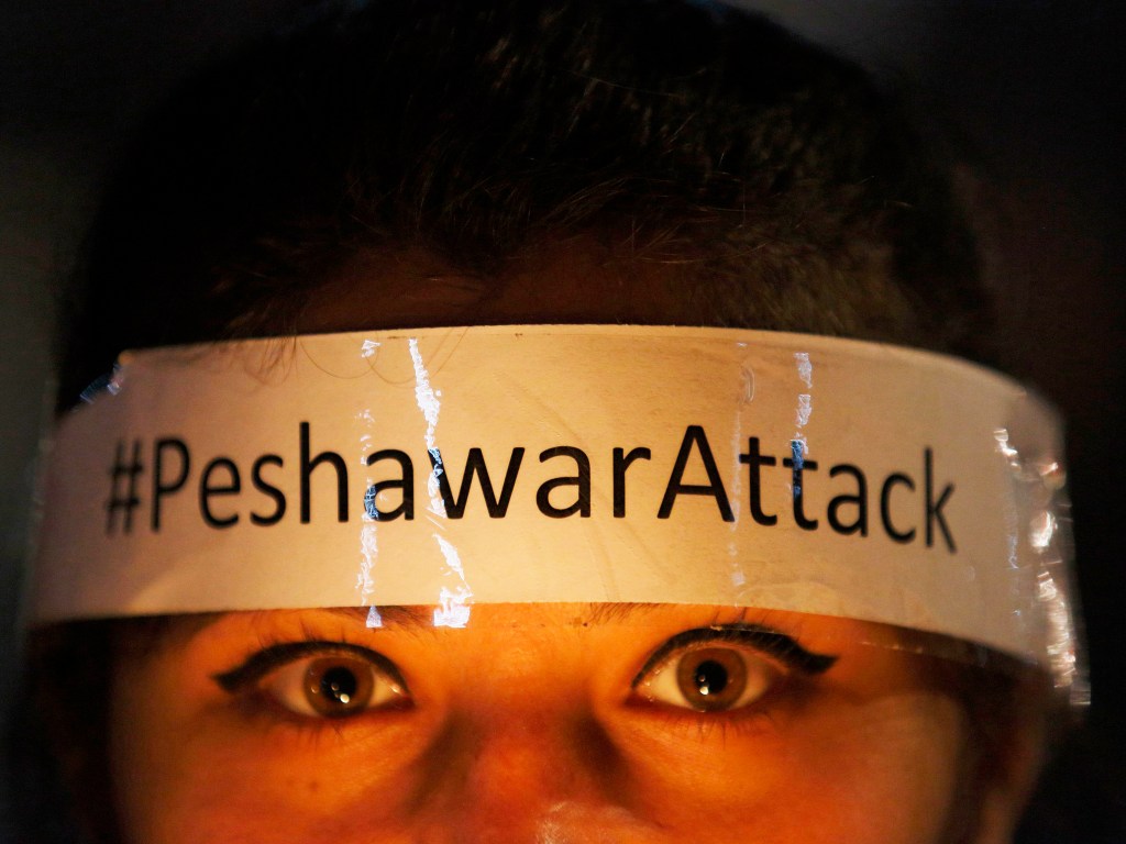 Mulher protesta contra o atentado que matou 132 estudantes no Paquistão