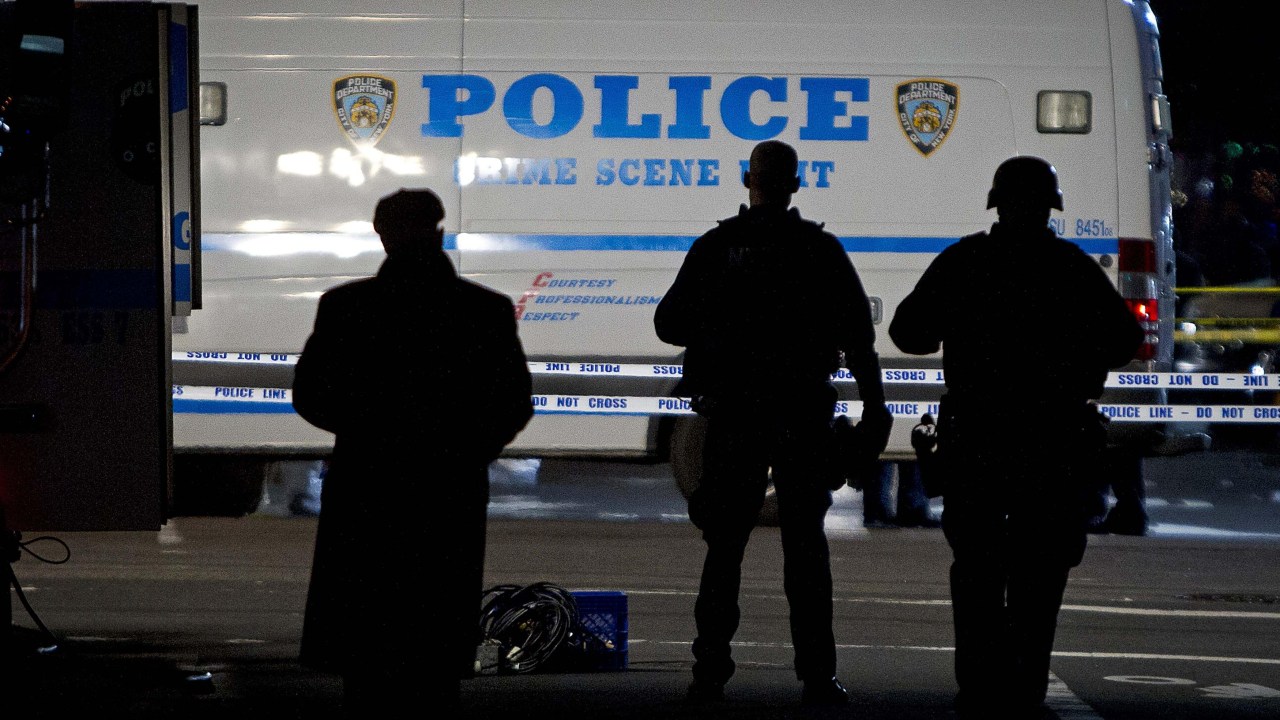Oficiais parados em frente ao local onde dois policiais de Nova York foram mortos a tiros, no bairro do Brooklyn