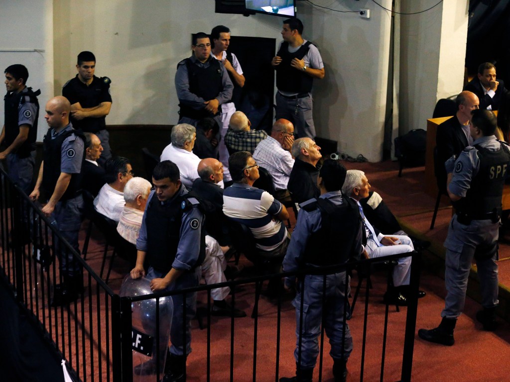 Alguns dos vinte e um homens acusados ​​de crimes contra a humanidade durante a ditadura militar da Argentina são fotografados na sala do tribunal de julgamento, na cidade de La Plata