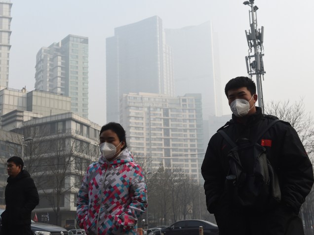 <p>Pessoas usam máscara para se proteger da poluição em Pequim, nesta segunda-feira (14)</p>
