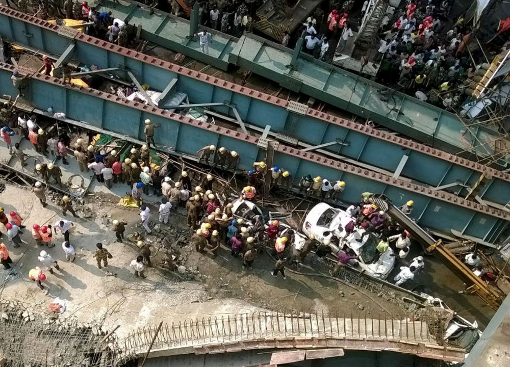 Curiosos e equipes de resgate perto da ponte de caiu em Calcutá, na Índia