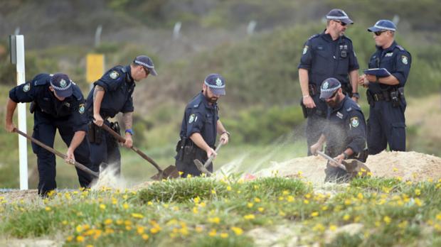 Policiais cavam a areia de uma praia em Sydney onde o corpo de um bebê foi encontrado