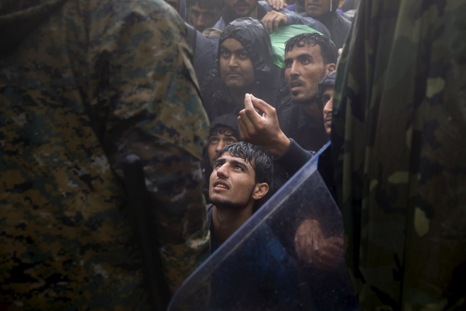 Imigrantes e refugiados imploram para policiais macedônios, para permitir a travessia entre a Grécia e a Macedônia, durante uma tempestade. Foto vencedora do prêmio Pulitzer, o maior prêmio do fotojornalismo - 10/09/2015