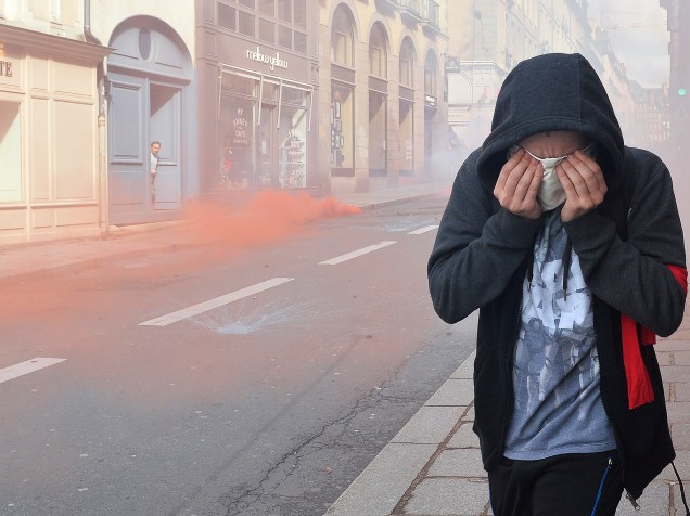 Manifestante protege o rosto, após a polícia lançar gás lacrimogêneo, durante protesto contra as reformas na legislação trabalhista, na cidade de Rennes, no noroeste da França, nesta quinta-feira (31)