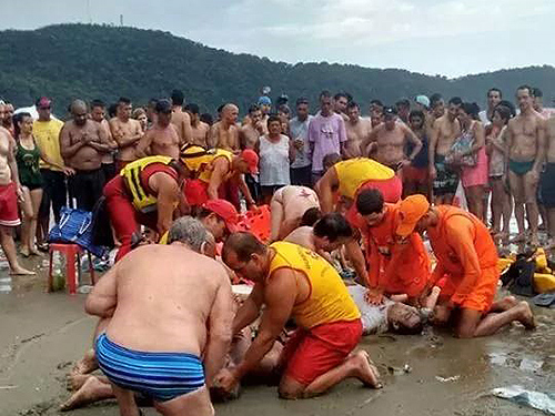 <p>Salva-mar tenta reanimar banhistas após raio atingir a praia do Canto do Forte, em Praia Grande (SP)</p>