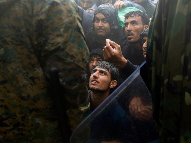 Refugiados sírios pedem a policial que libere passagem na fronteira da Macedônia, nesta quinta-feira (10)