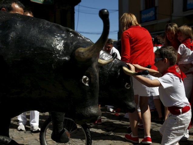 Garoto para um touro de brinquedo durante o "Encierro Txiki", a "pequena corrida de touros", no Festival de São Firmino, em Pamplona, Espanha